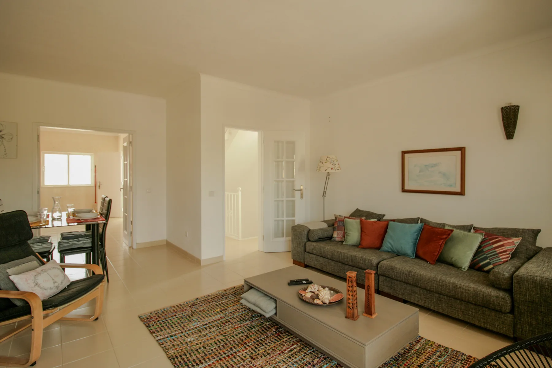 A living room with seating around a coffee table and an open dining area.