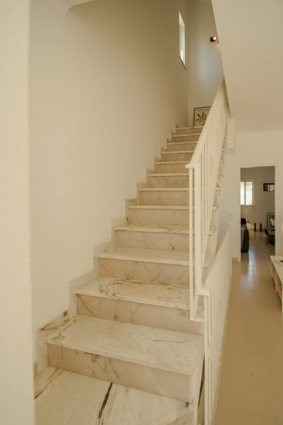 Una escalera revestida de baldosas con barandilla blanca conduce a la planta superior.