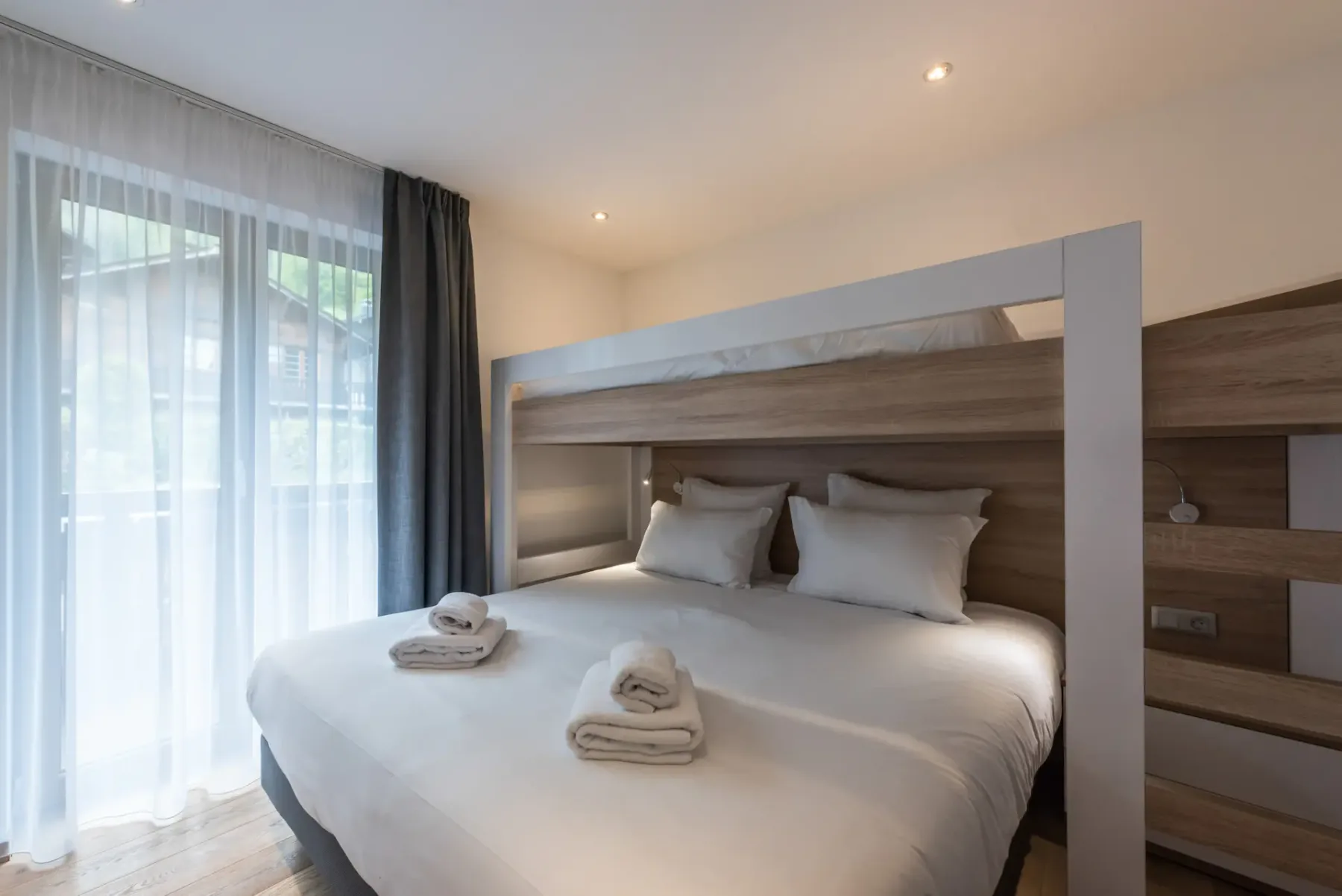 A bedroom with a large bed, white bedding, and sheer curtains.
