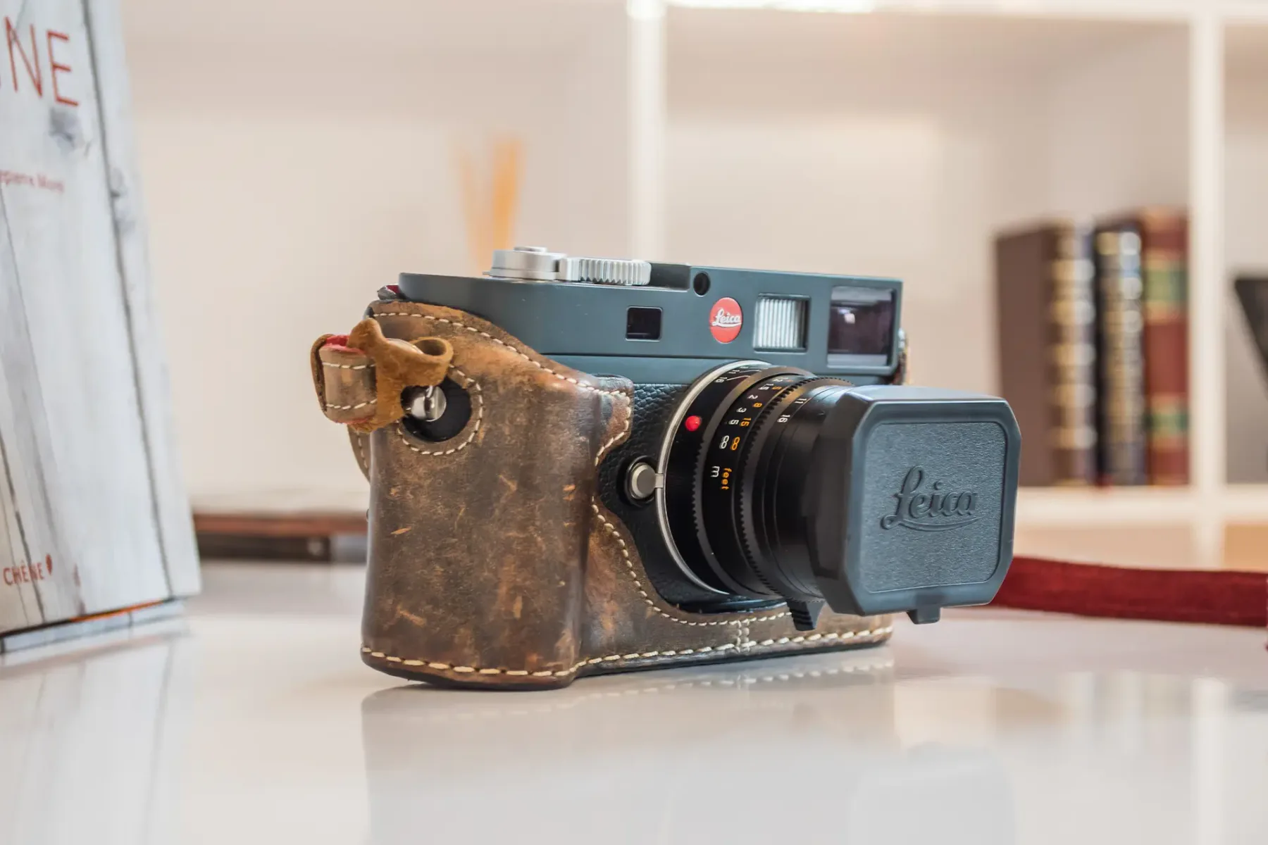 Una cámara de película antigua con una funda de cuero desgastada está sobre una mesa.