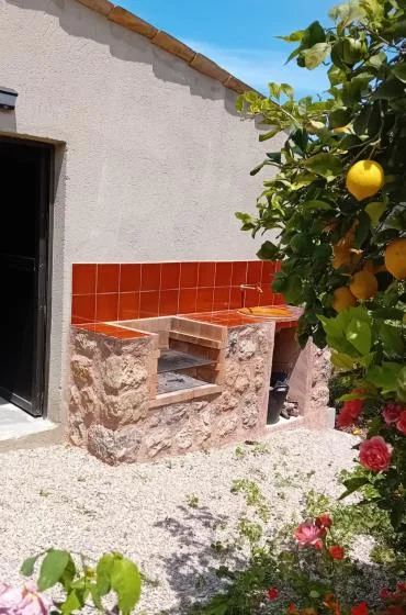 An outdoor tiled counter stands beside a citrus tree in a gravel courtyard.