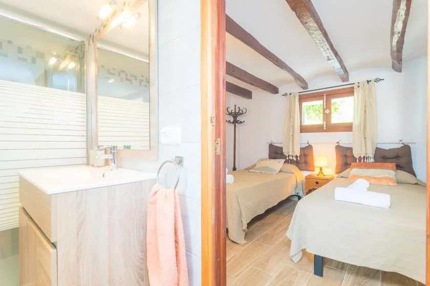 A bedroom with two beds and a washbasin area beside the doorway.