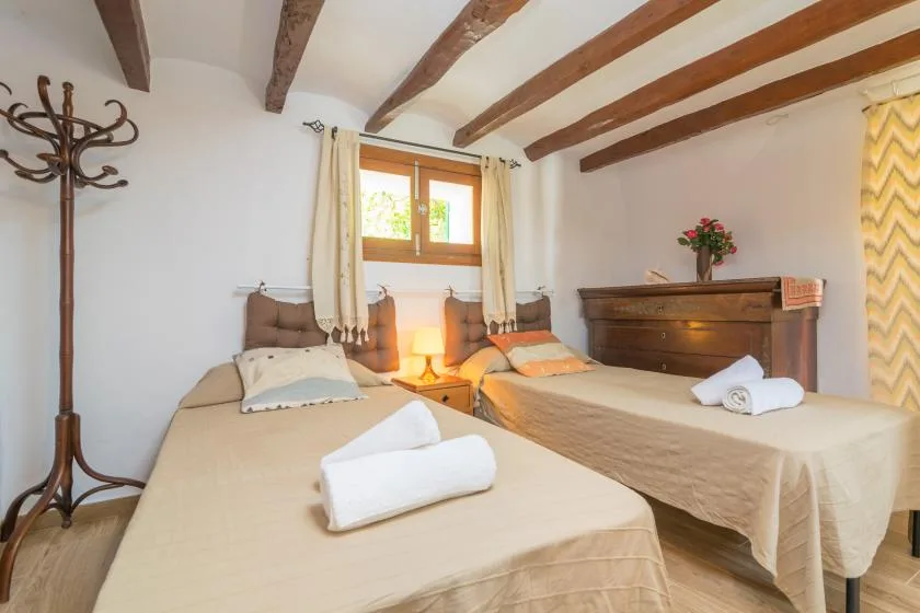 A bedroom with two beds and exposed wooden ceiling beams.
