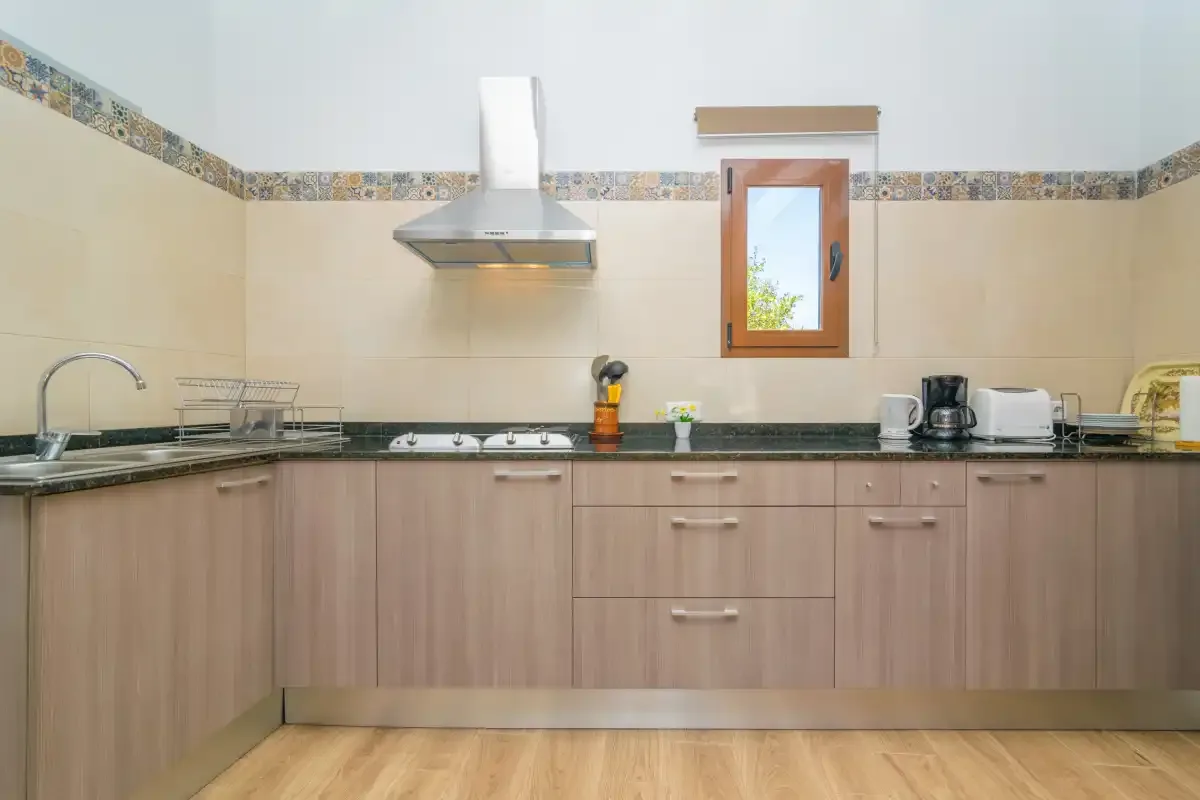 A kitchen with light wood cabinets and a dark countertop.