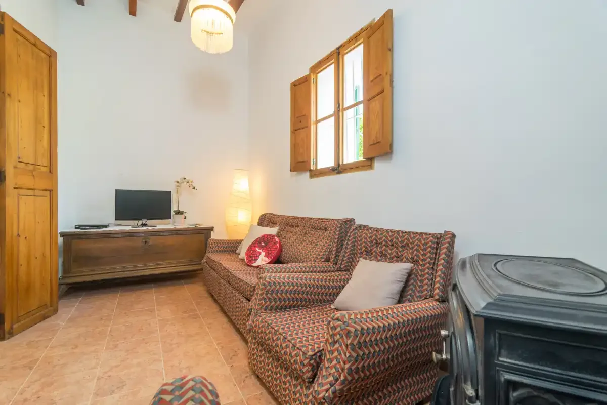 A living room with patterned seating, a television, and wooden shutters.