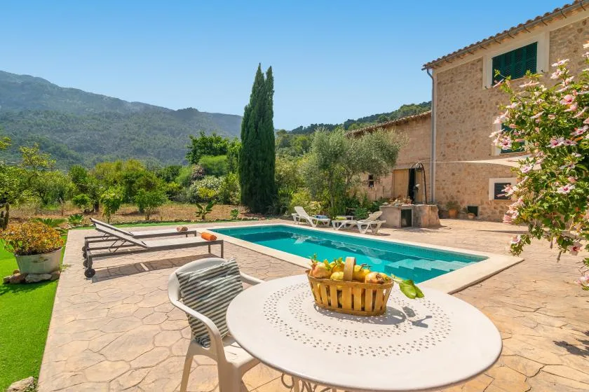 An outdoor pool area with lounge seating beside a stone building.
