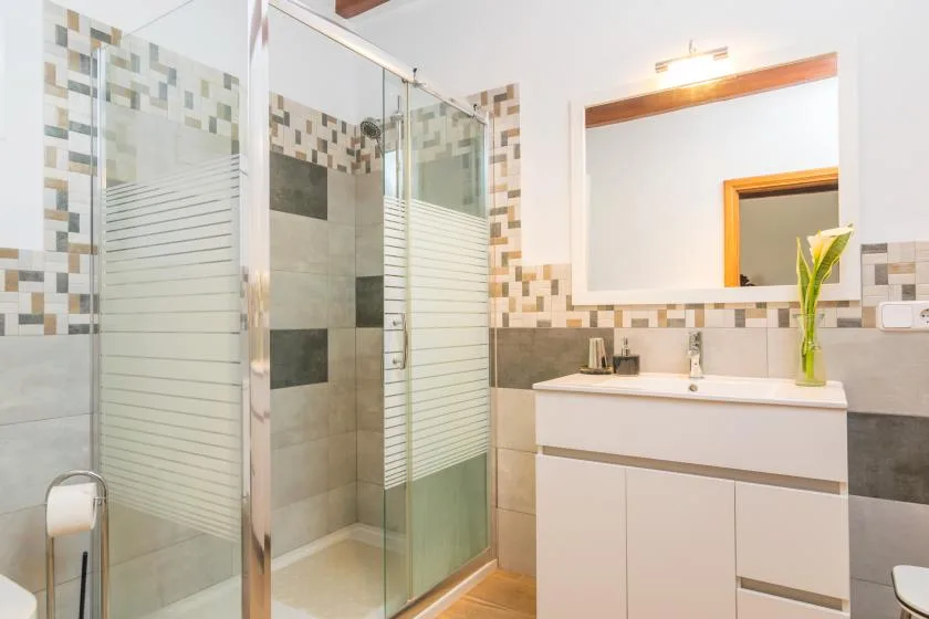 A bathroom with a glass shower and a vanity topped with a sink.