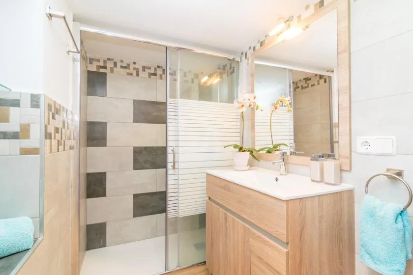 A tiled bathroom with a glass shower, vanity, and sink.