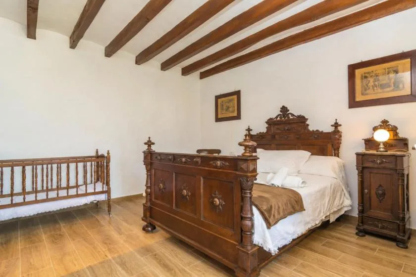 A bedroom with a wooden bed, matching bedside furniture, and exposed ceiling beams.