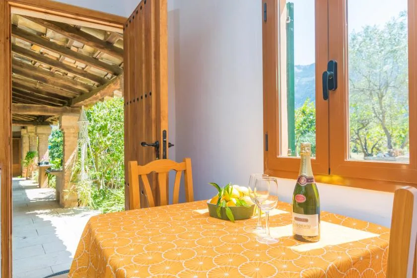 A dining table with a yellow cloth sits beside open doors overlooking a covered patio.