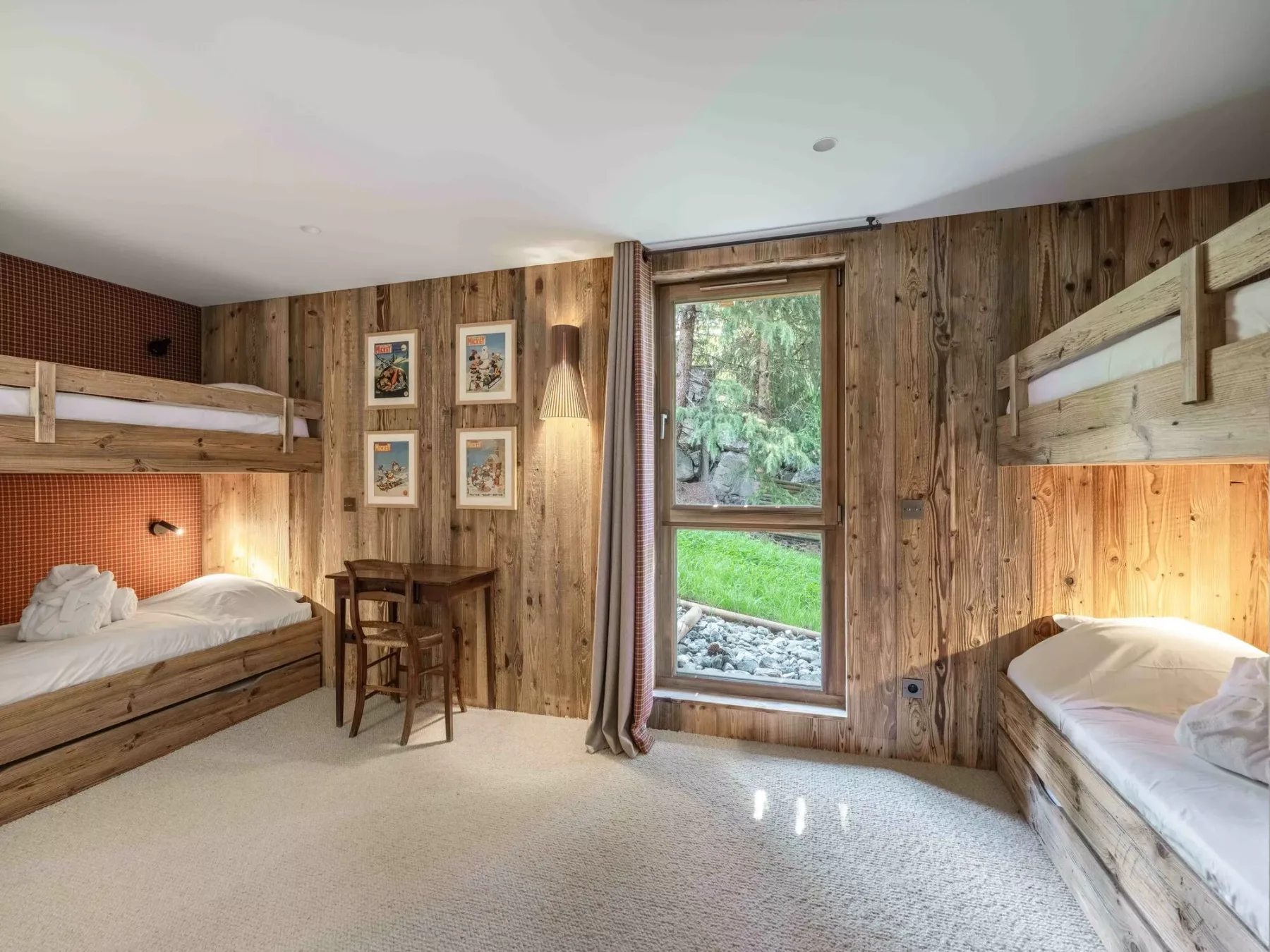A wood-paneled bedroom with built-in bunk beds and a window overlooking greenery.