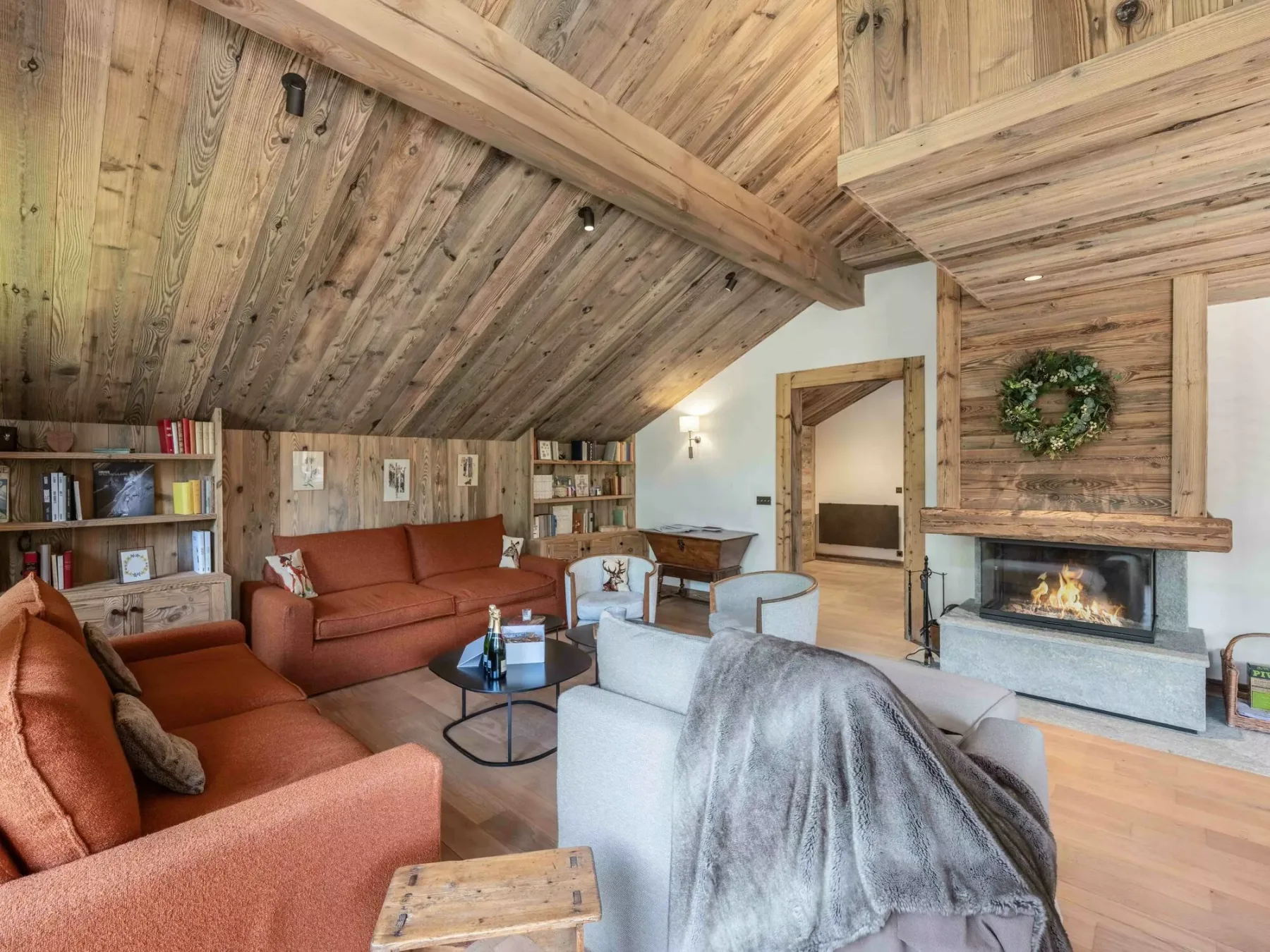 Una sala de estar con asientos, estanterías y una chimenea bajo un techo abovedado de madera.