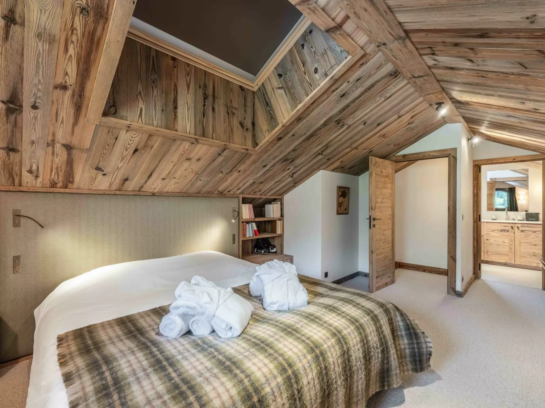 A bedroom with a bed beneath a sloped wooden ceiling.
