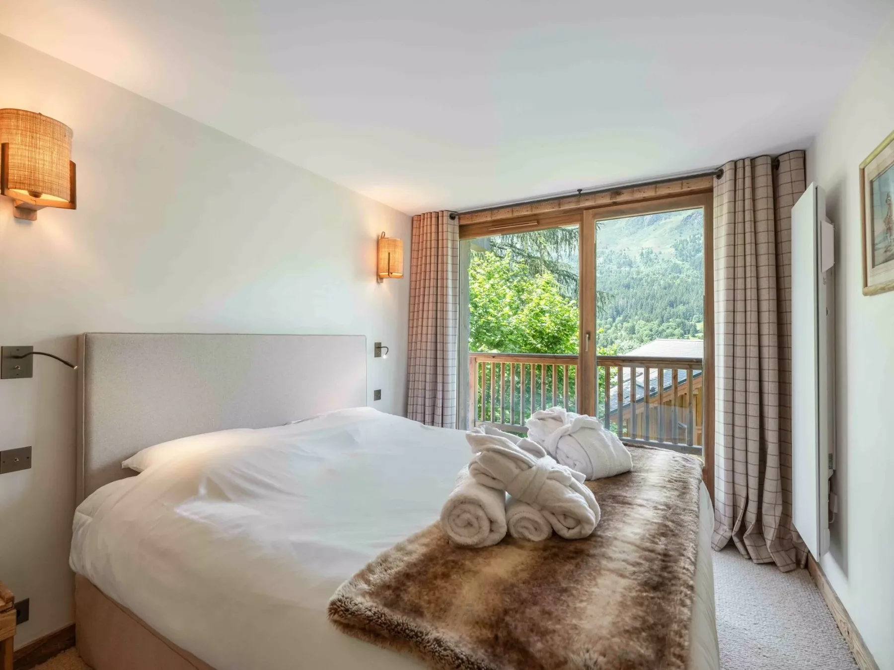 A bedroom with a large bed and a window overlooking green hills.