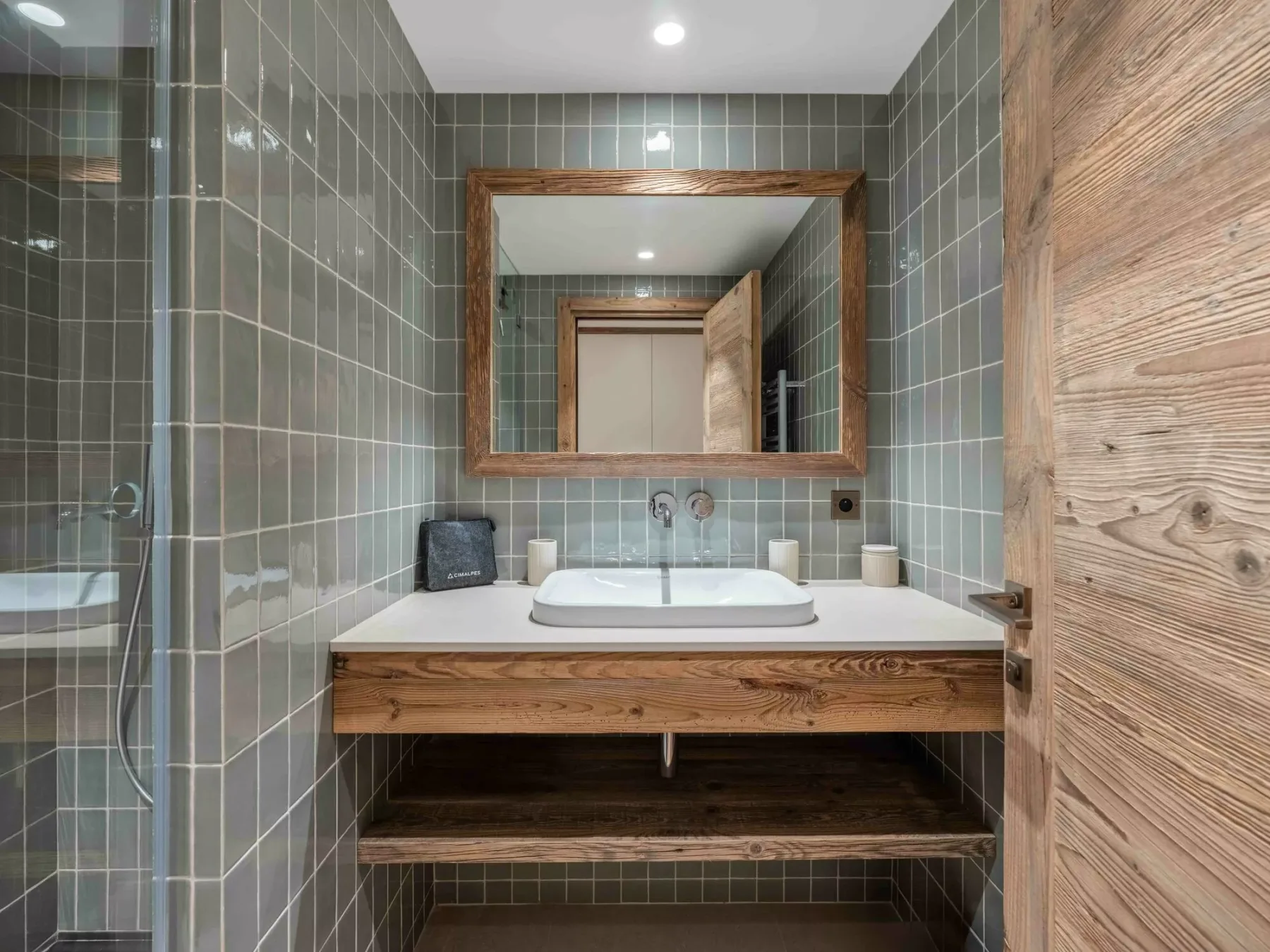 A tiled bathroom vanity with a white sink and wood-framed mirror.