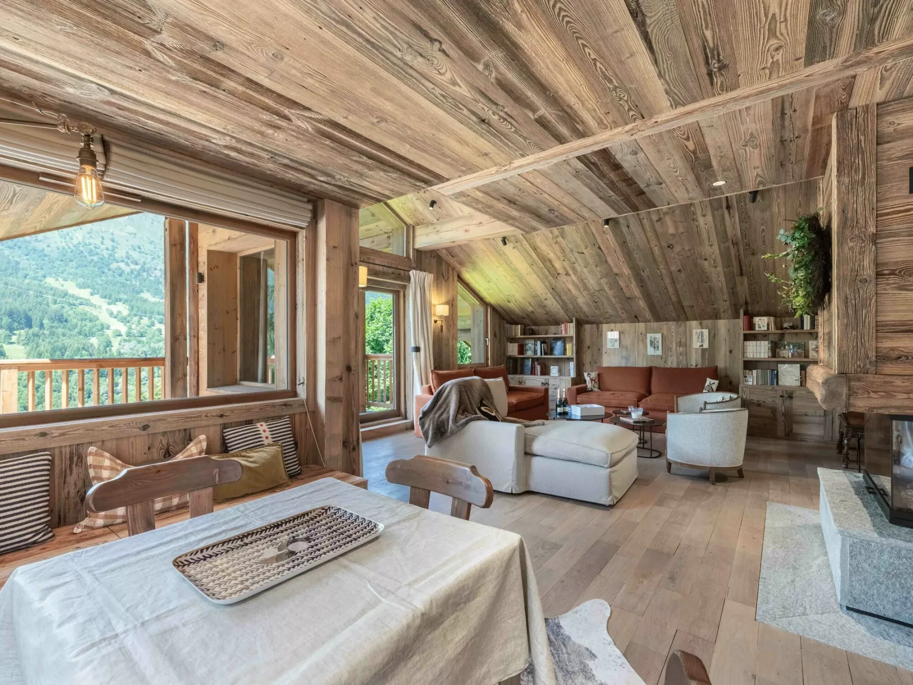 A wood-paneled living room with seating and a dining table beside large windows.
