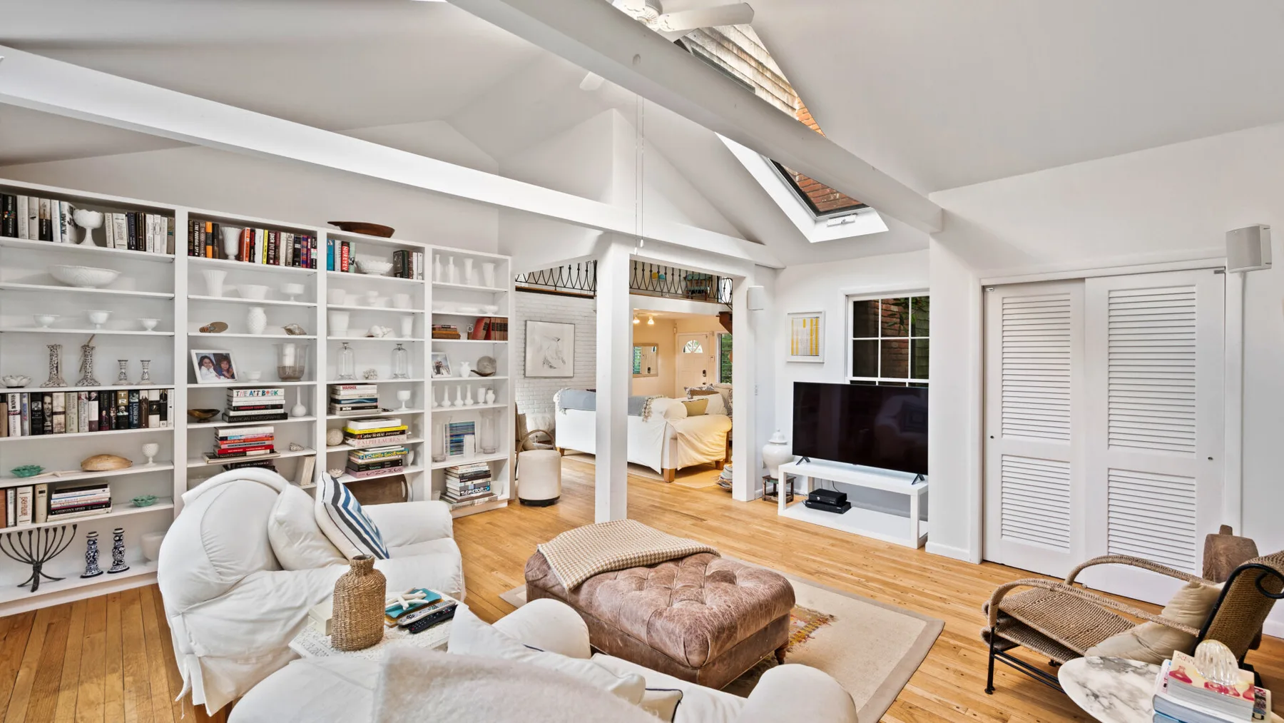A bright living room with built-in bookshelves, seating, and a television.