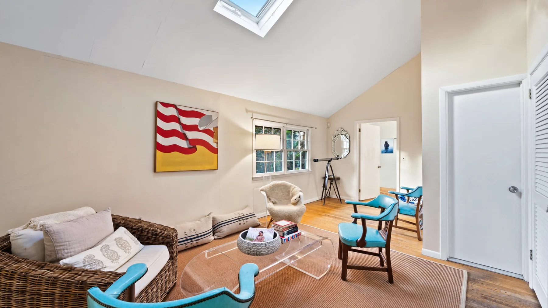 A bright living room with wicker seating, a glass coffee table, and a skylight.