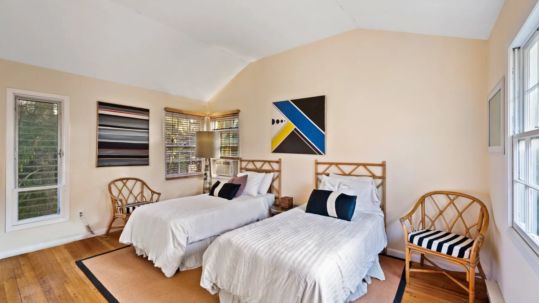 A bright bedroom with two beds and wooden seating.