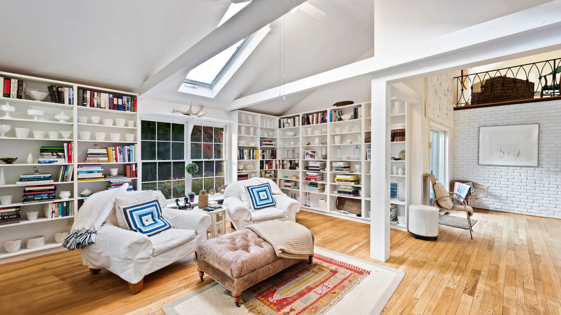 A bright living room with built-in bookshelves, seating, and a skylight.