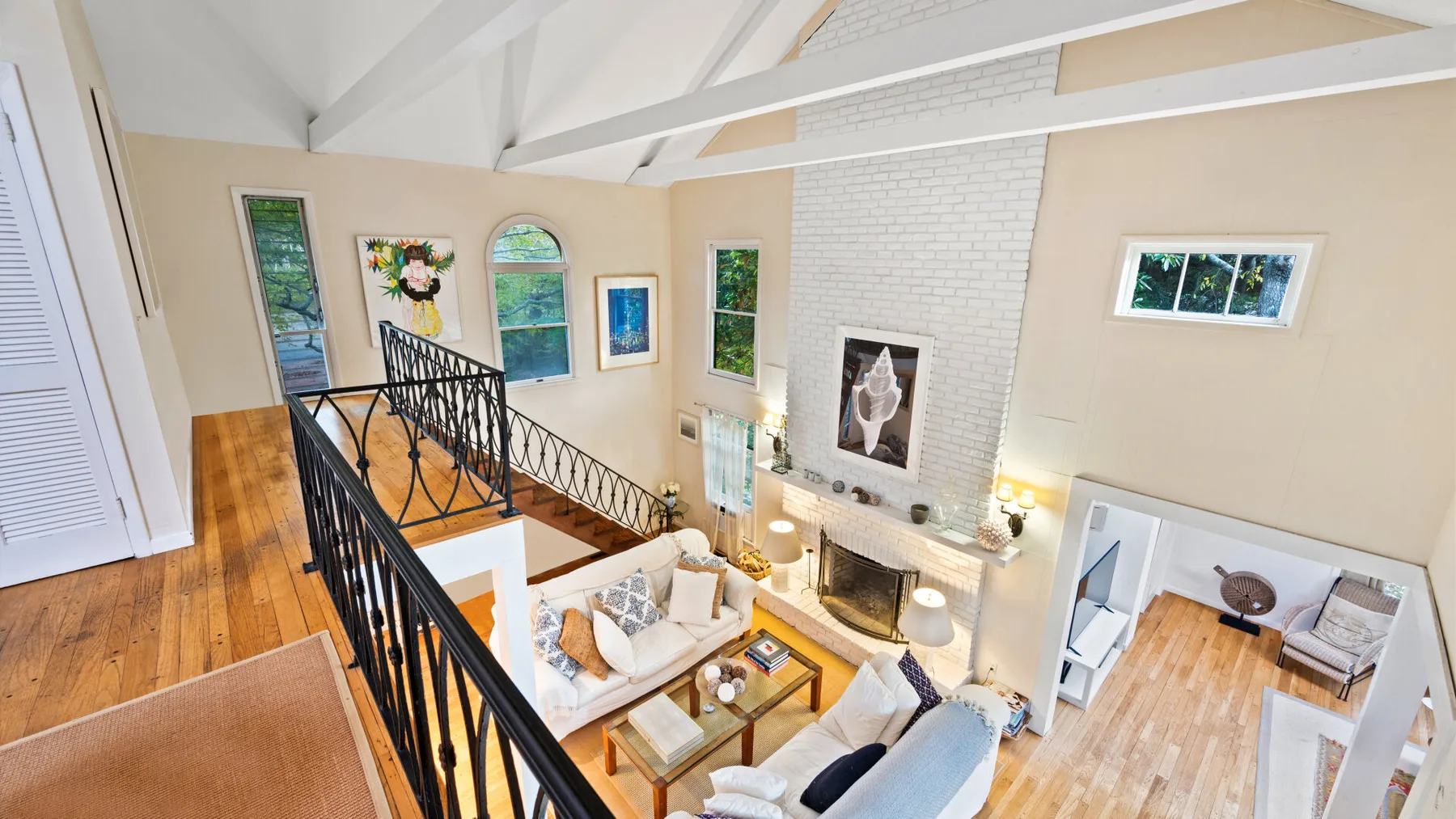 A bright open living room with a fireplace and seating beneath a vaulted ceiling.
