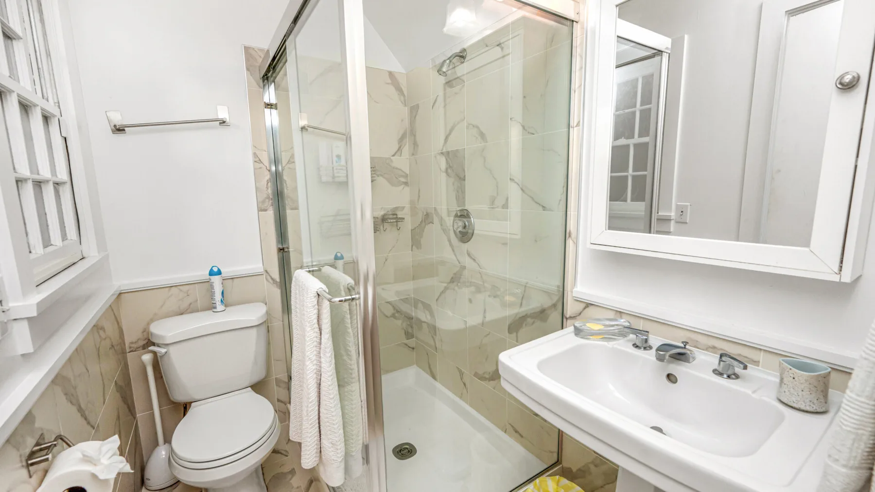 A bright bathroom with a glass shower, toilet, and sink.