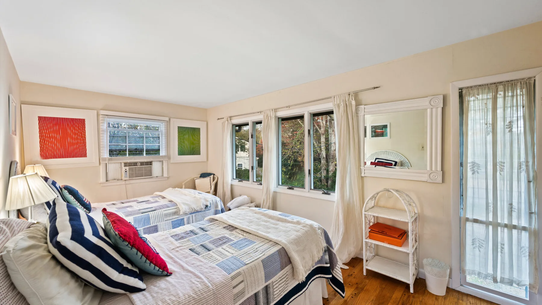 A bedroom with two beds, patterned bedding, and large windows.