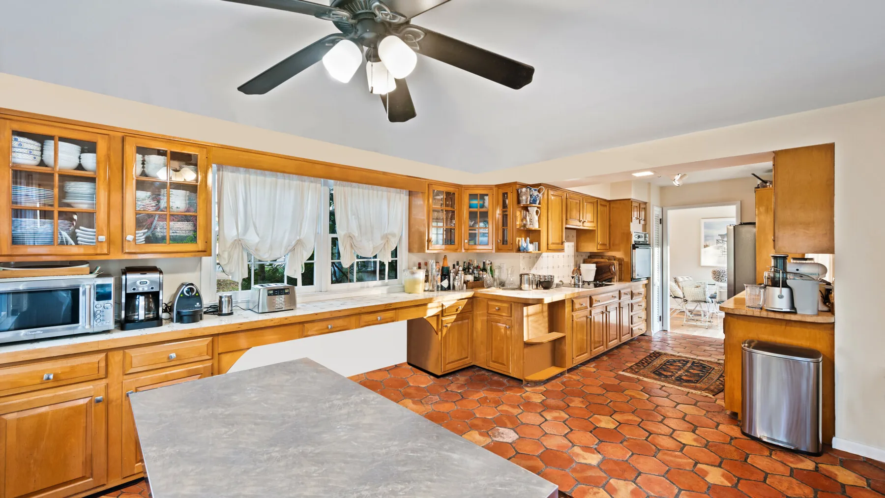A spacious kitchen with wooden cabinets, countertops, and a ceiling fan.