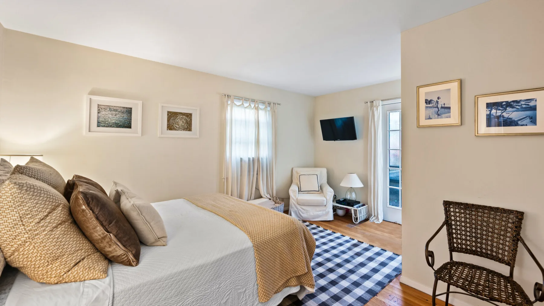A bedroom with a bed, a checkered rug, and a chair by the window.