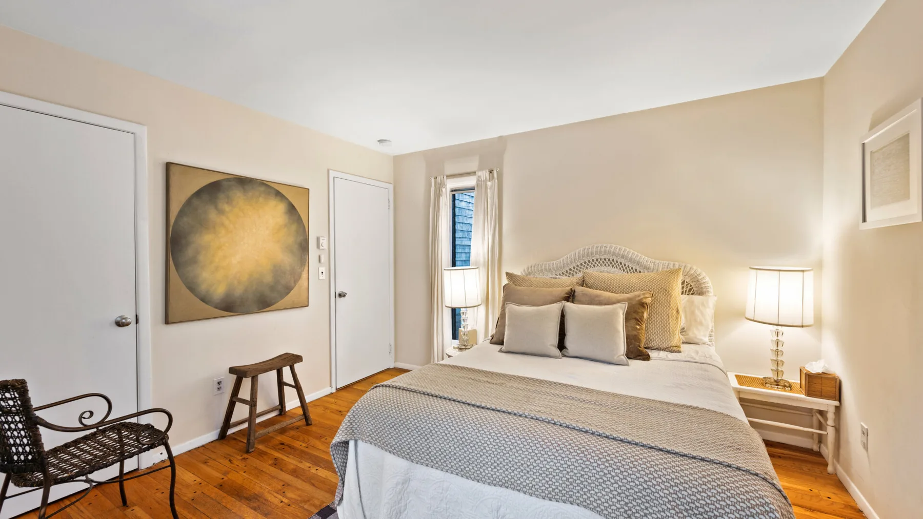 A bedroom with a neatly made bed and framed artwork on the wall.