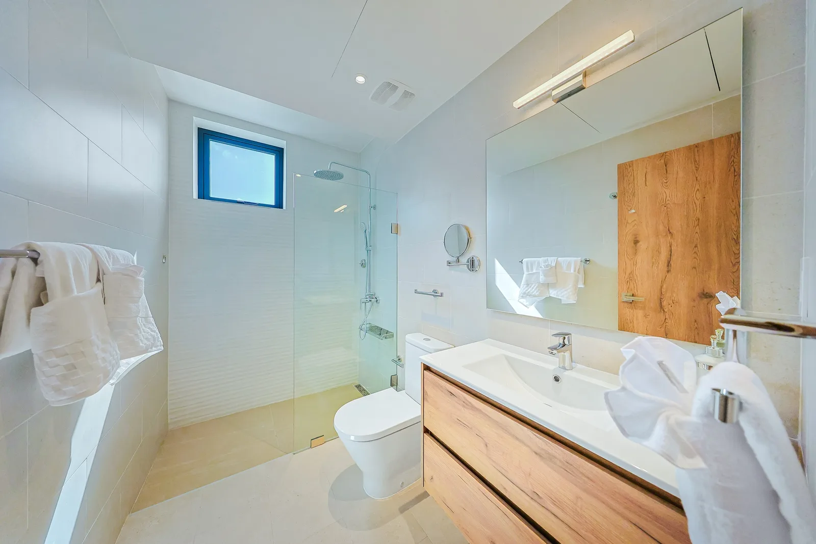 Your modern bathroom features a spacious glass-enclosed shower and sleek wood-accent vanity, creating a warm, spa-like atmosphere perfect for unwinding after a day of adventure.