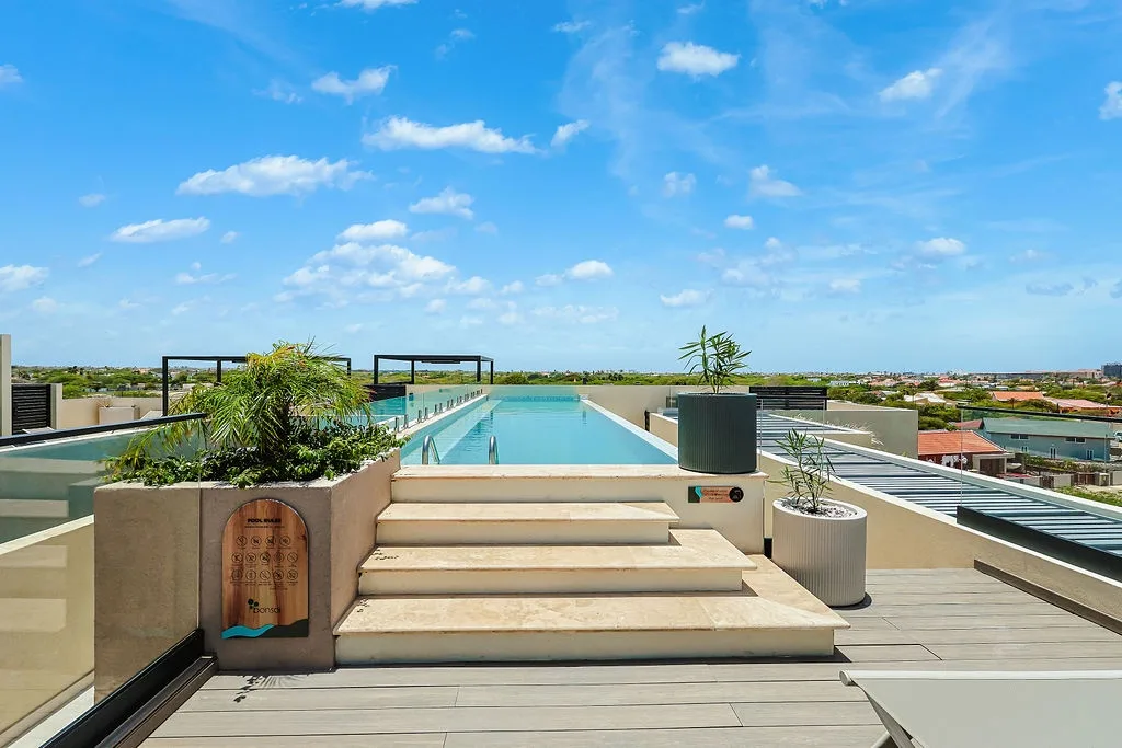A stunning rooftop oasis awaits, featuring a sleek lap pool framed by lush greenery and expansive views. Ascend the sun-warmed steps and immerse yourself in this serene escape above the city.