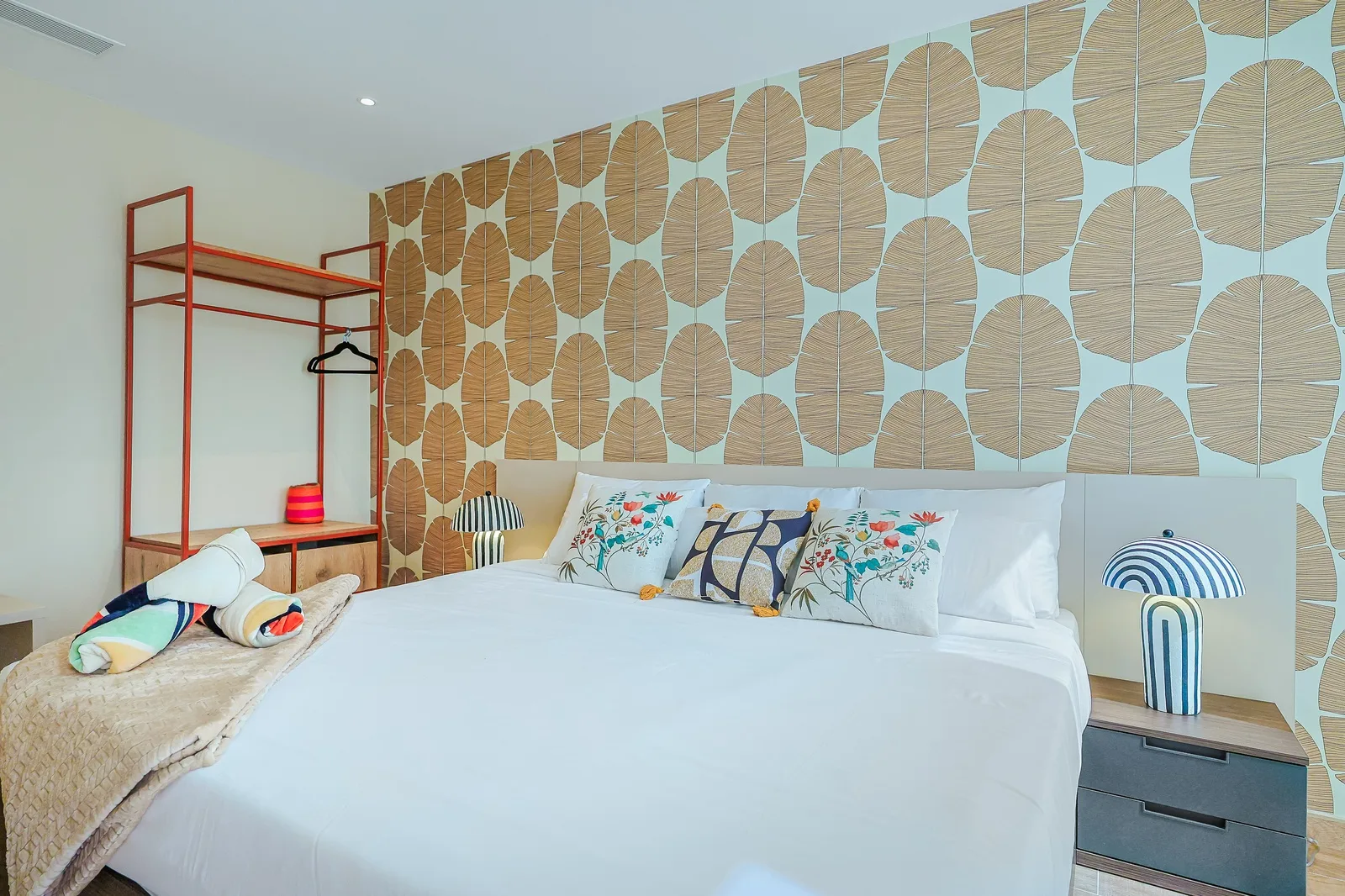 Relax in your plush king size bed under crisp white linens, surrounded by playful tropical accents and a soothing leaf-patterned accent wall that brings the outdoors in.