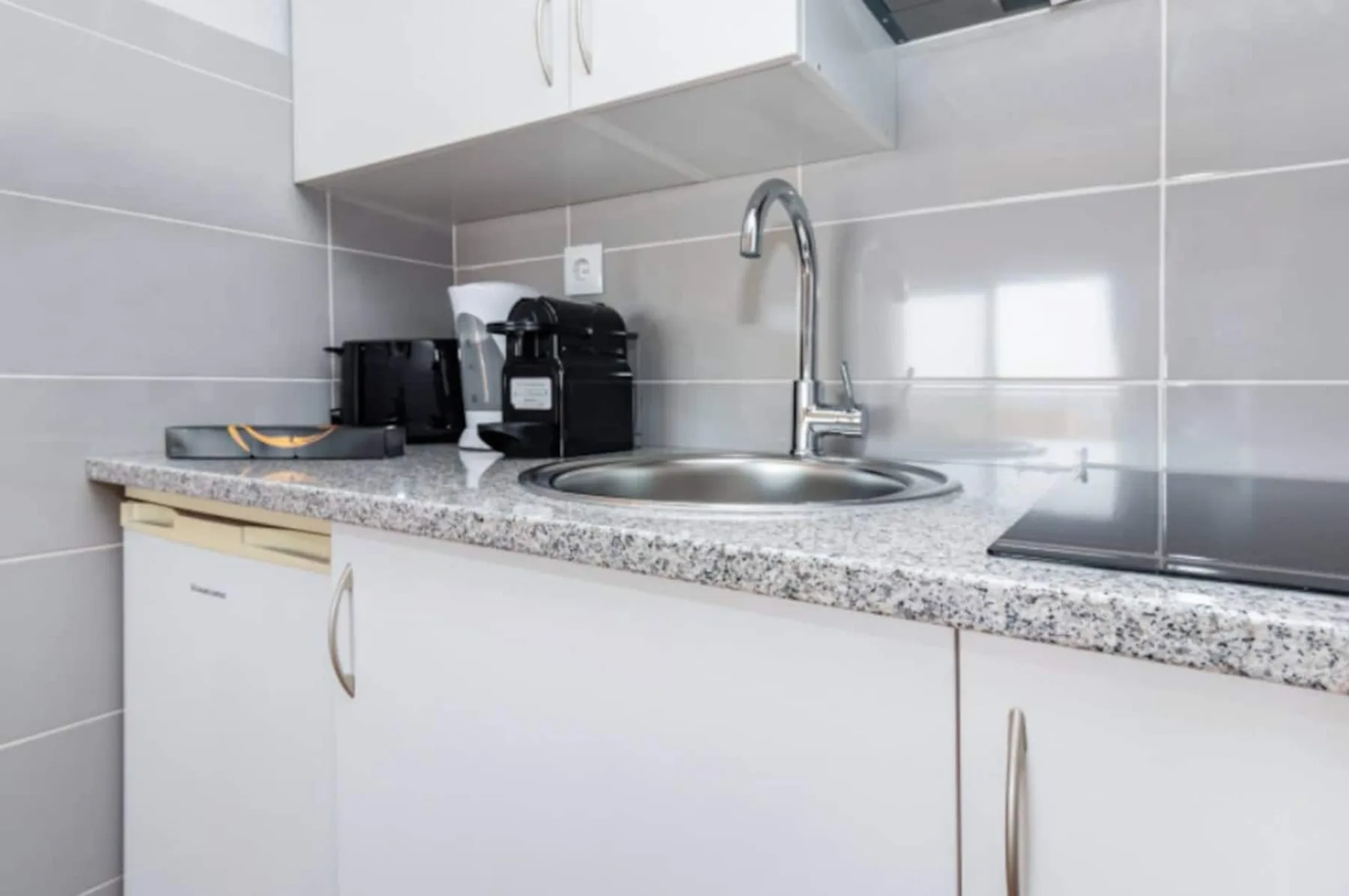A compact kitchen counter with a sink, faucet, and coffee maker.