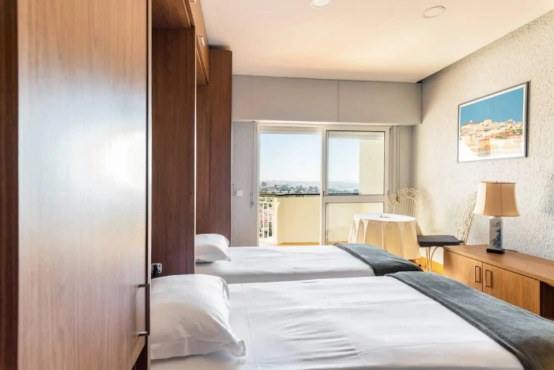 A bedroom with two beds and a window overlooking the city.