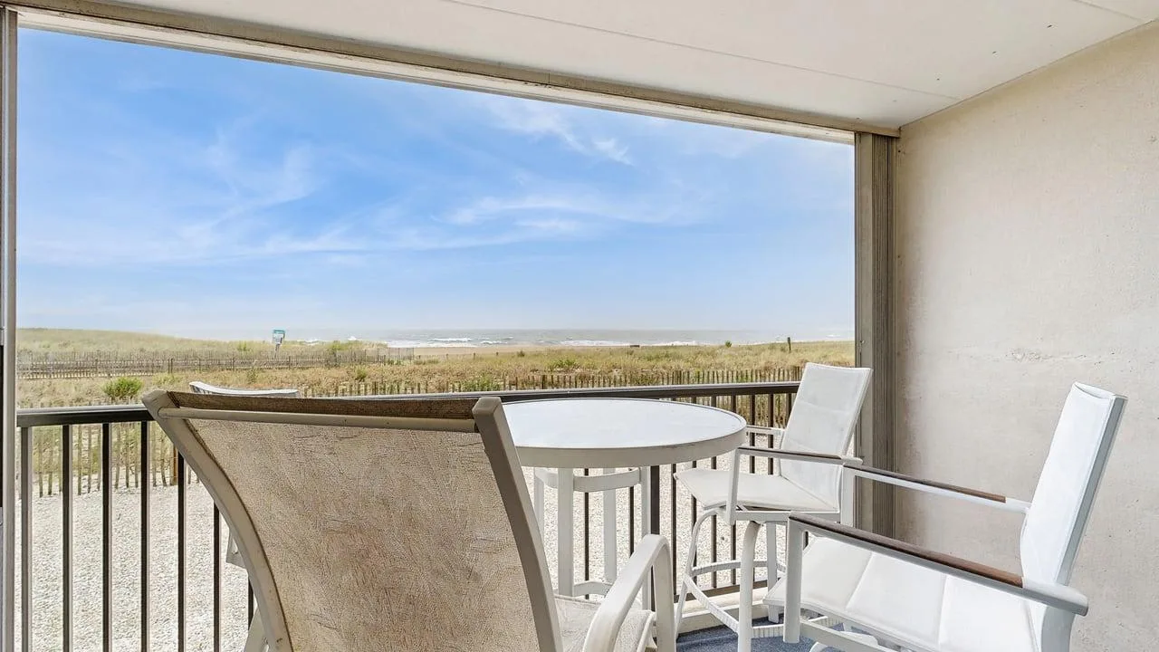 A balcony seating area overlooks an open landscape beneath a blue sky.
