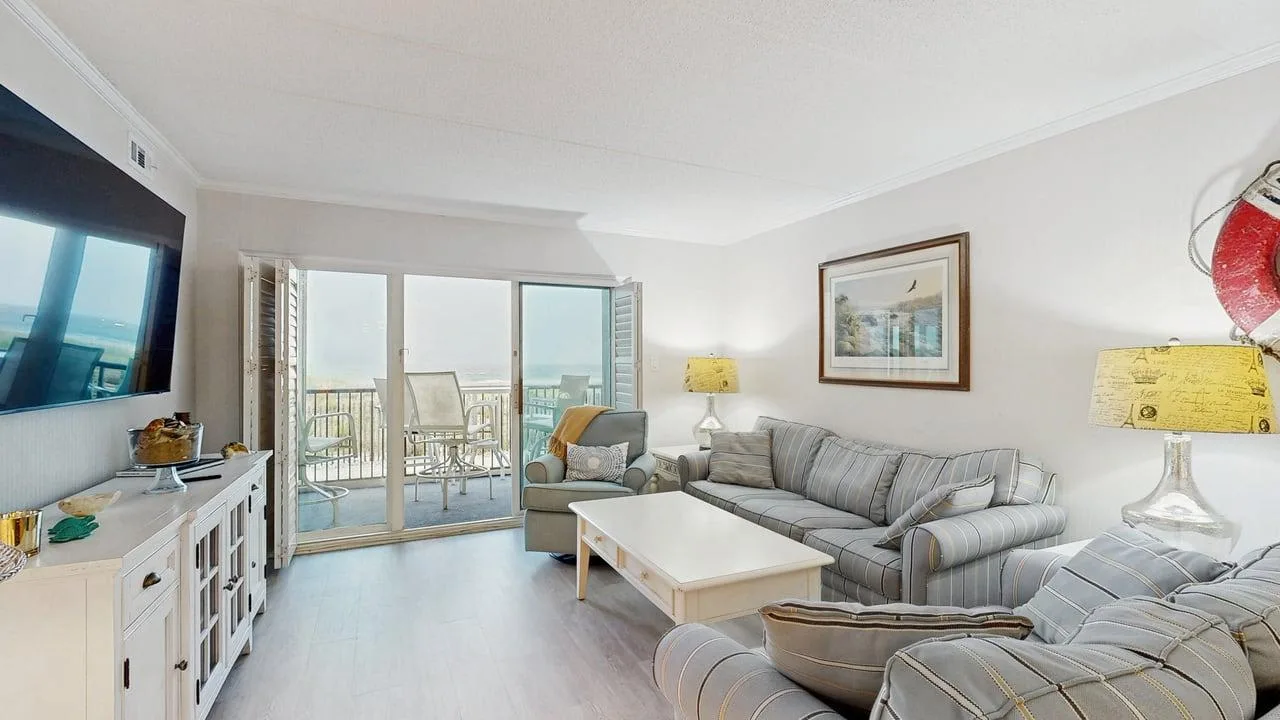 A bright living room with seating, a coffee table, and sliding glass doors.