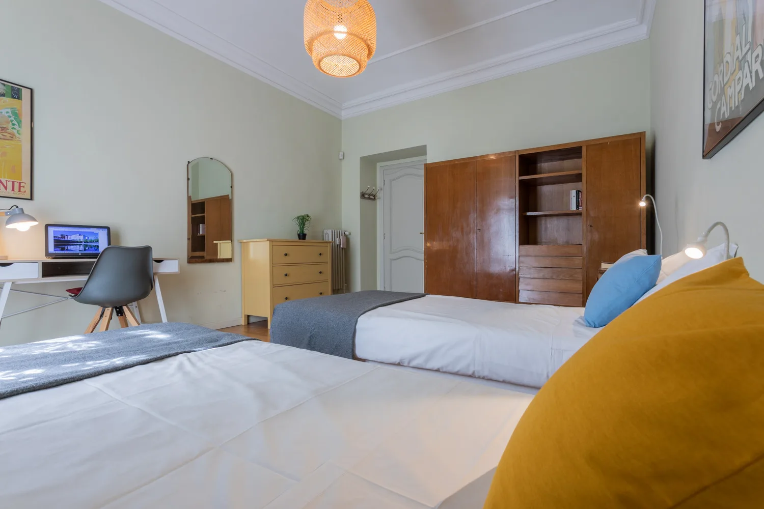 A bedroom with two beds, a desk, and wooden storage.