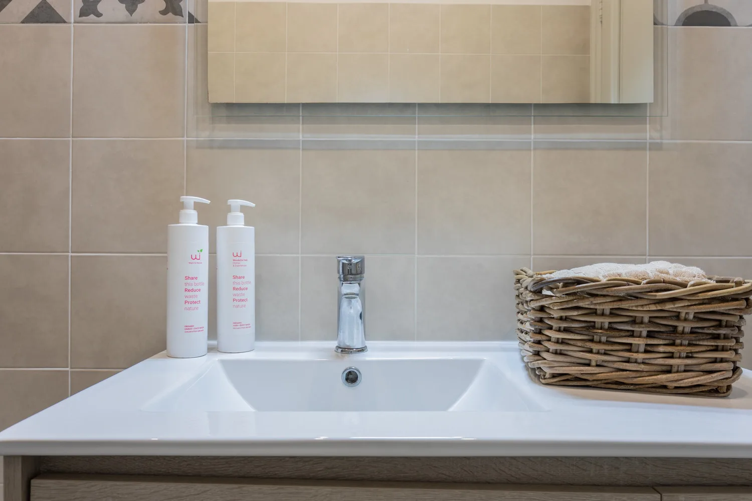 A bathroom sink with toiletries and a wicker basket on the counter.