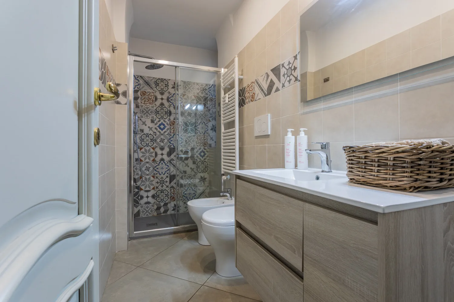 A bathroom with a sink vanity, toilet, and glass shower.