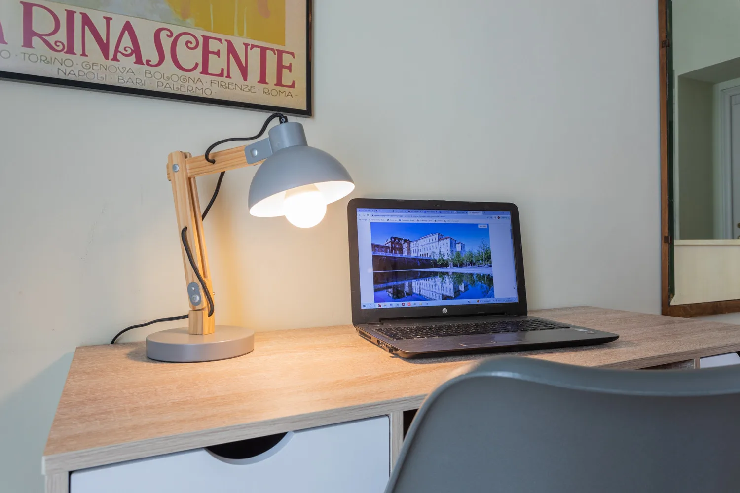 A desk workspace with a lit lamp and an open laptop.