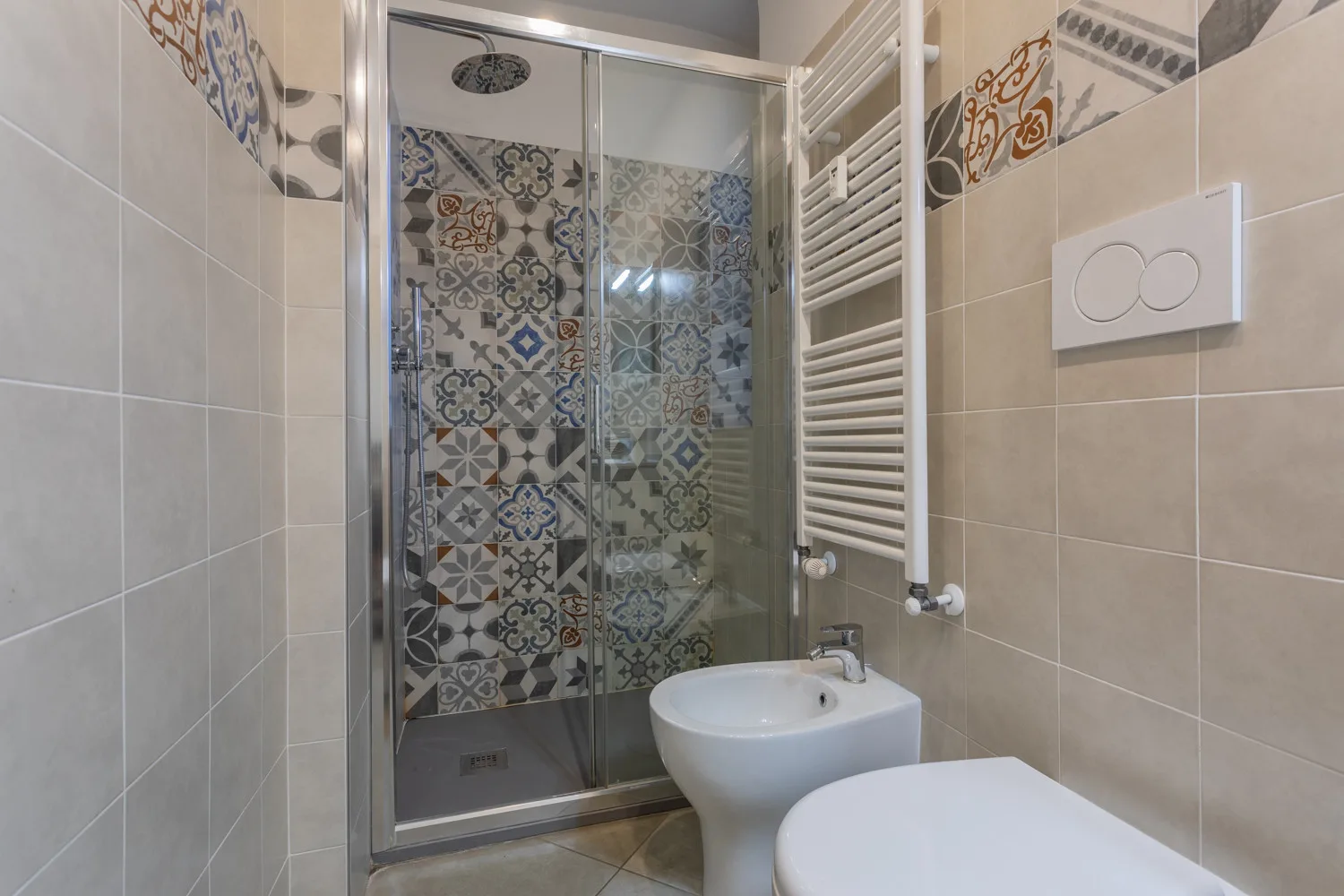 A tiled bathroom with a glass shower and a bidet.