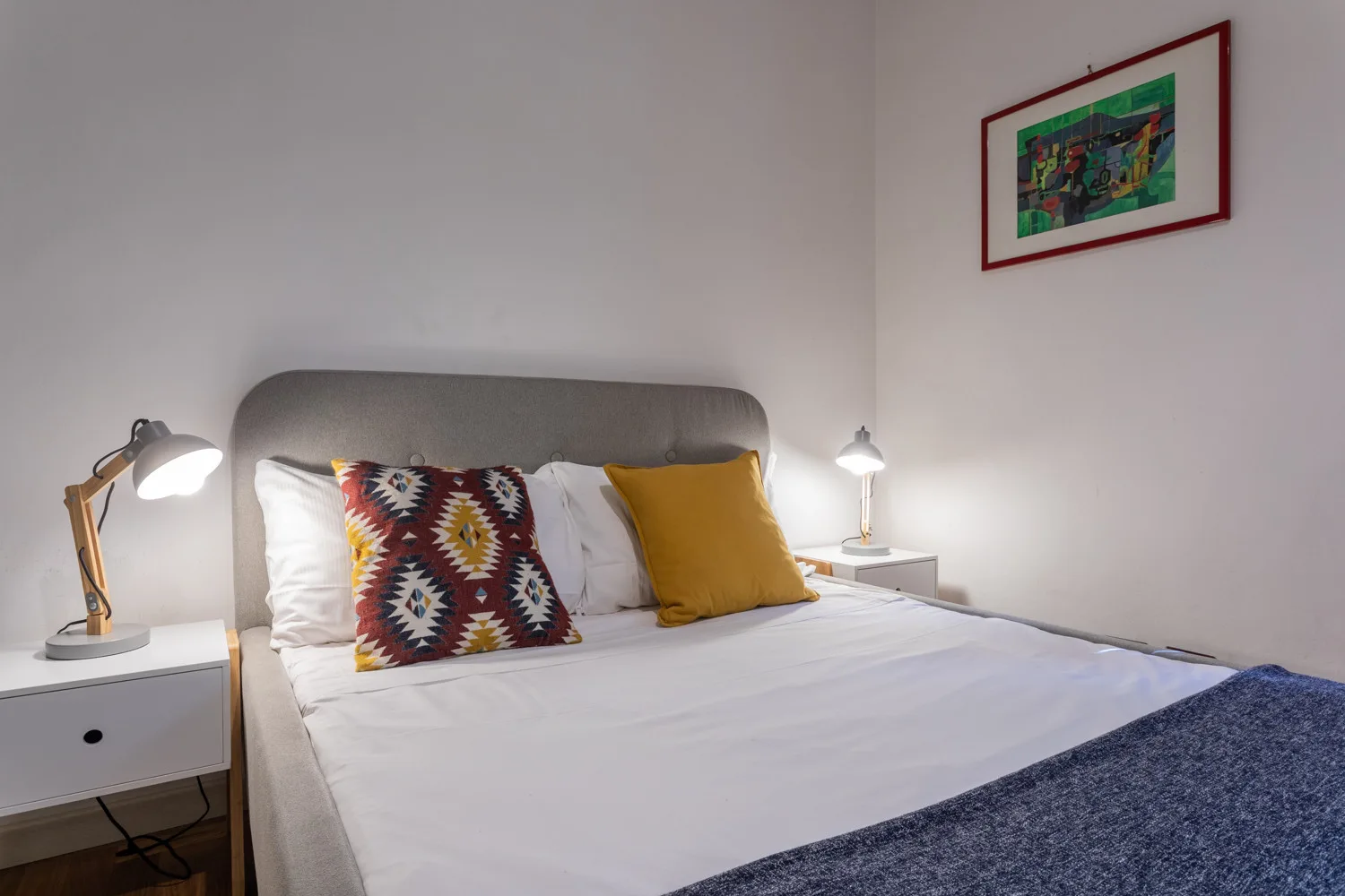 A bedroom with a neatly made bed and colorful accent pillows.