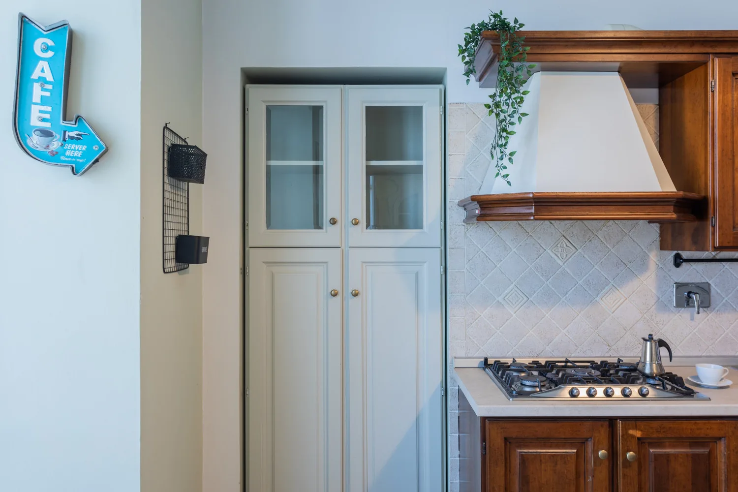A kitchen with wooden cabinetry, a gas cooktop, and a tall white cabinet.