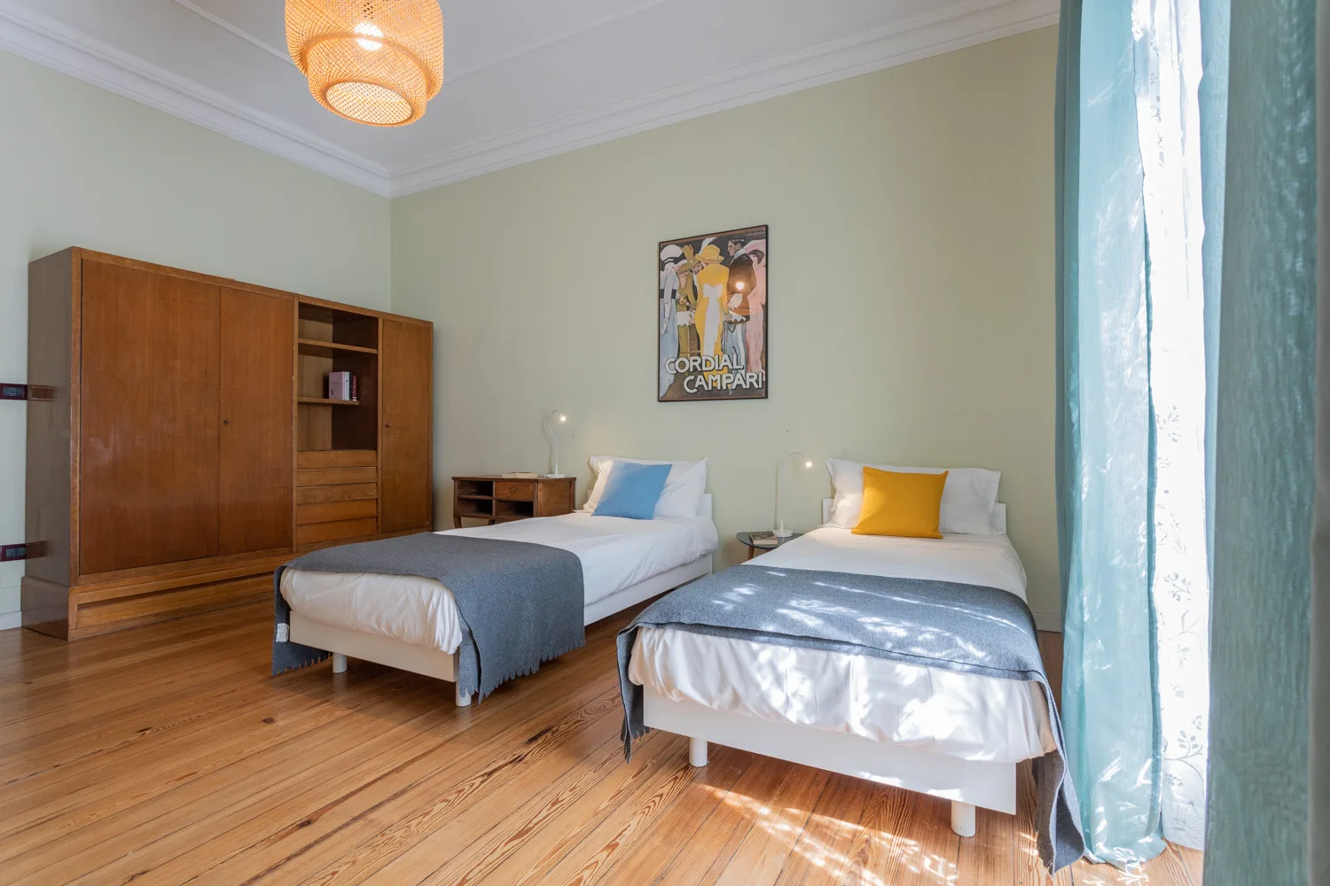 A bedroom with two beds, wooden flooring, and a large wardrobe.