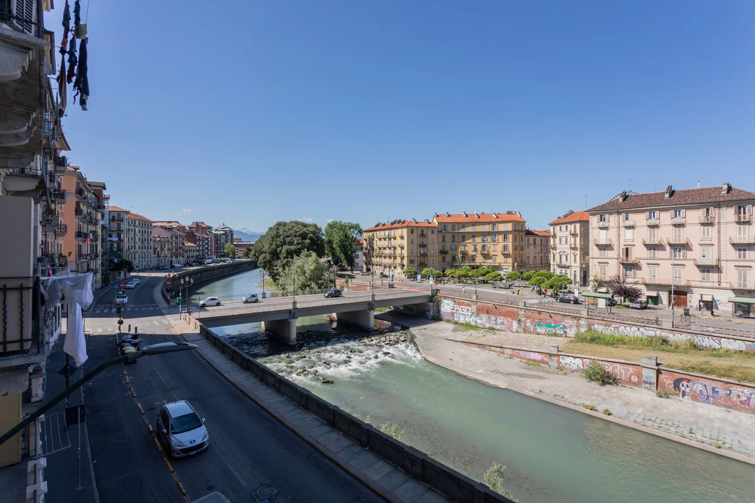 An urban canal runs beneath a bridge, with buildings lining the banks.