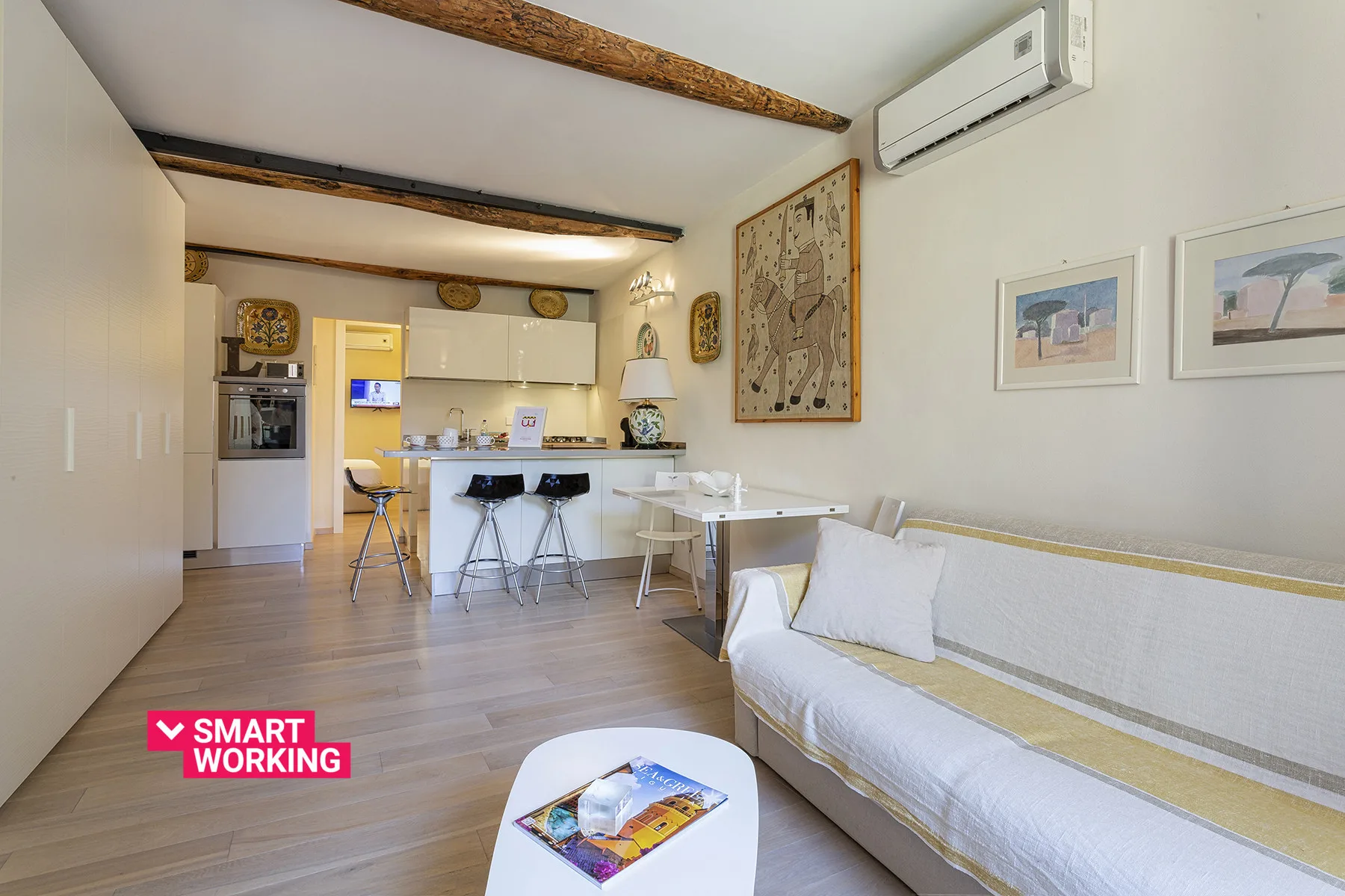 Una luminosa sala de estar se abre a una cocina compacta, con un sofá y una barra de comedor.