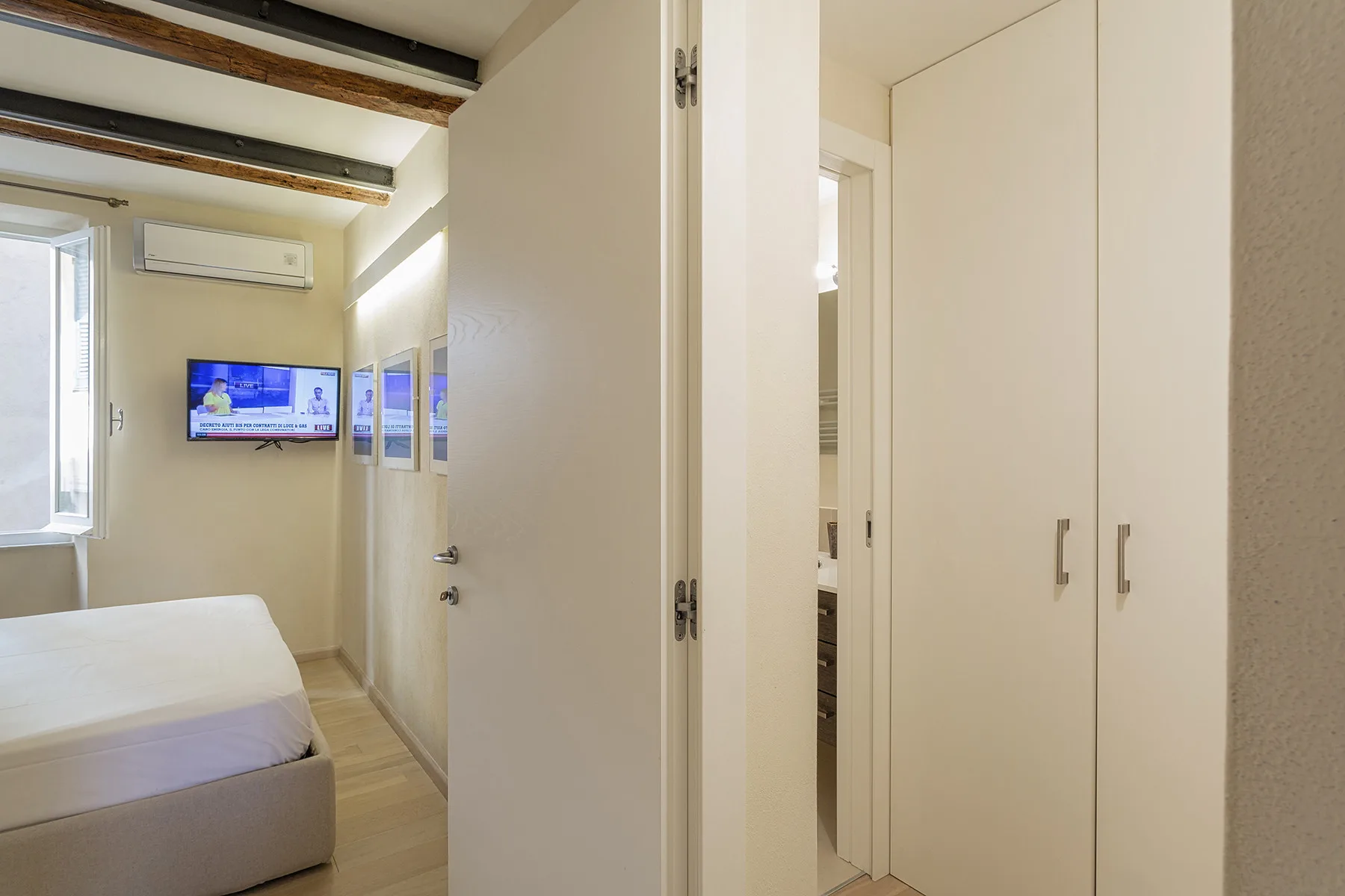 Un dormitorio con una cama, un televisor en la pared y armarios empotrados.