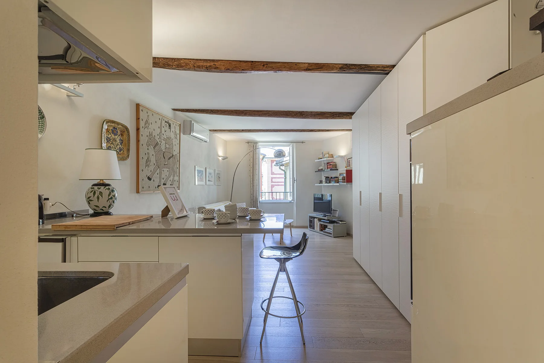 Una cocina y comedor luminosos se abren hacia una sala con una puerta al balcón.
