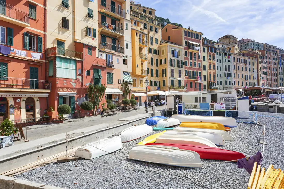 Un paseo marítimo bordeado de edificios coloridos y pequeñas embarcaciones en la orilla.